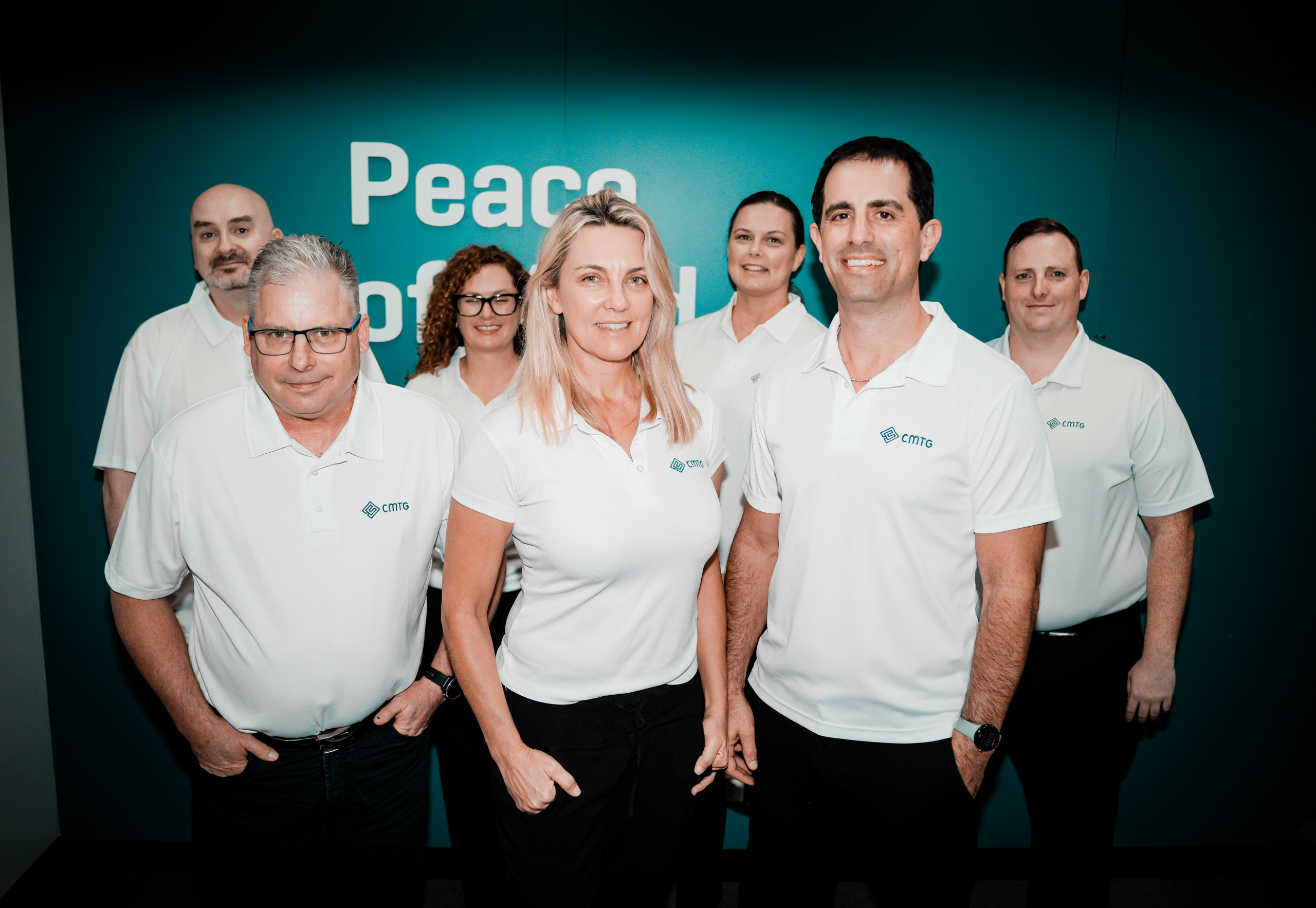 CMTG group in white shirts smiling and posing together for a photo, representing IT support in Perth.