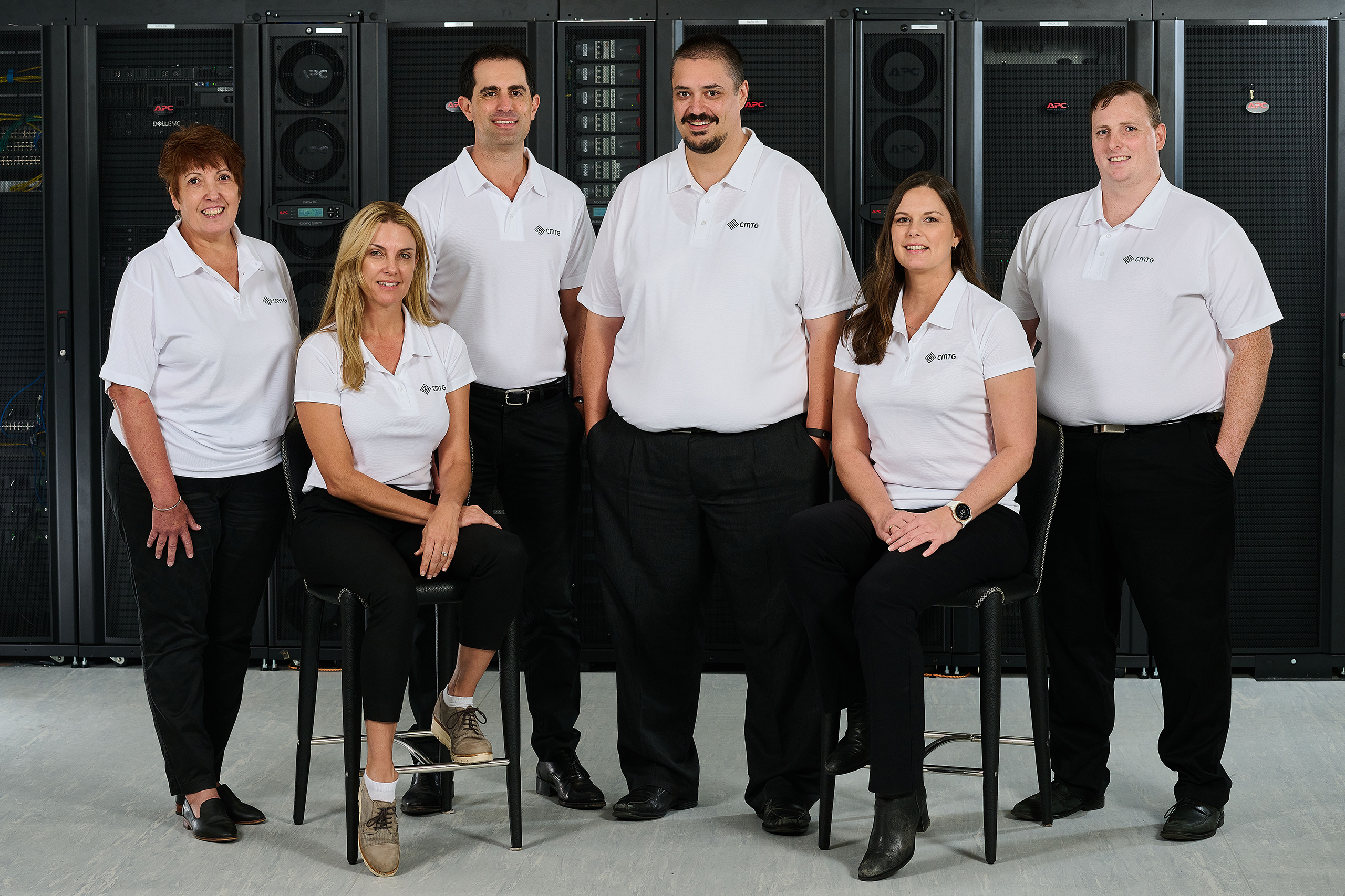 A group of individuals in white shirts smiling and posing together for a photo, representing IT support in Perth.