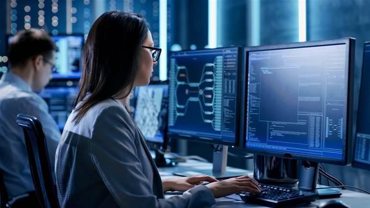 Woman working on multiple monitors in a modern office providing cyber security Perth services for government industries.