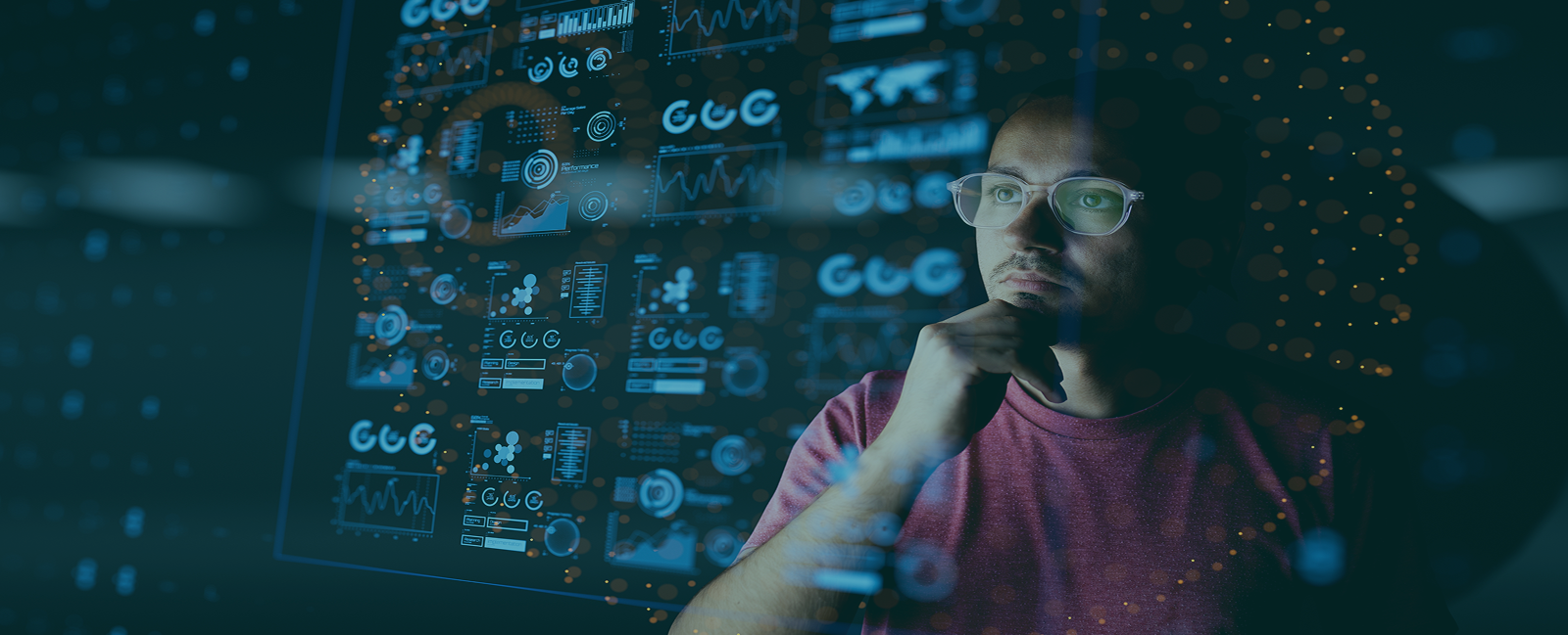 A man wearing glasses intently examines a computer screen, focused on IT support tasks.