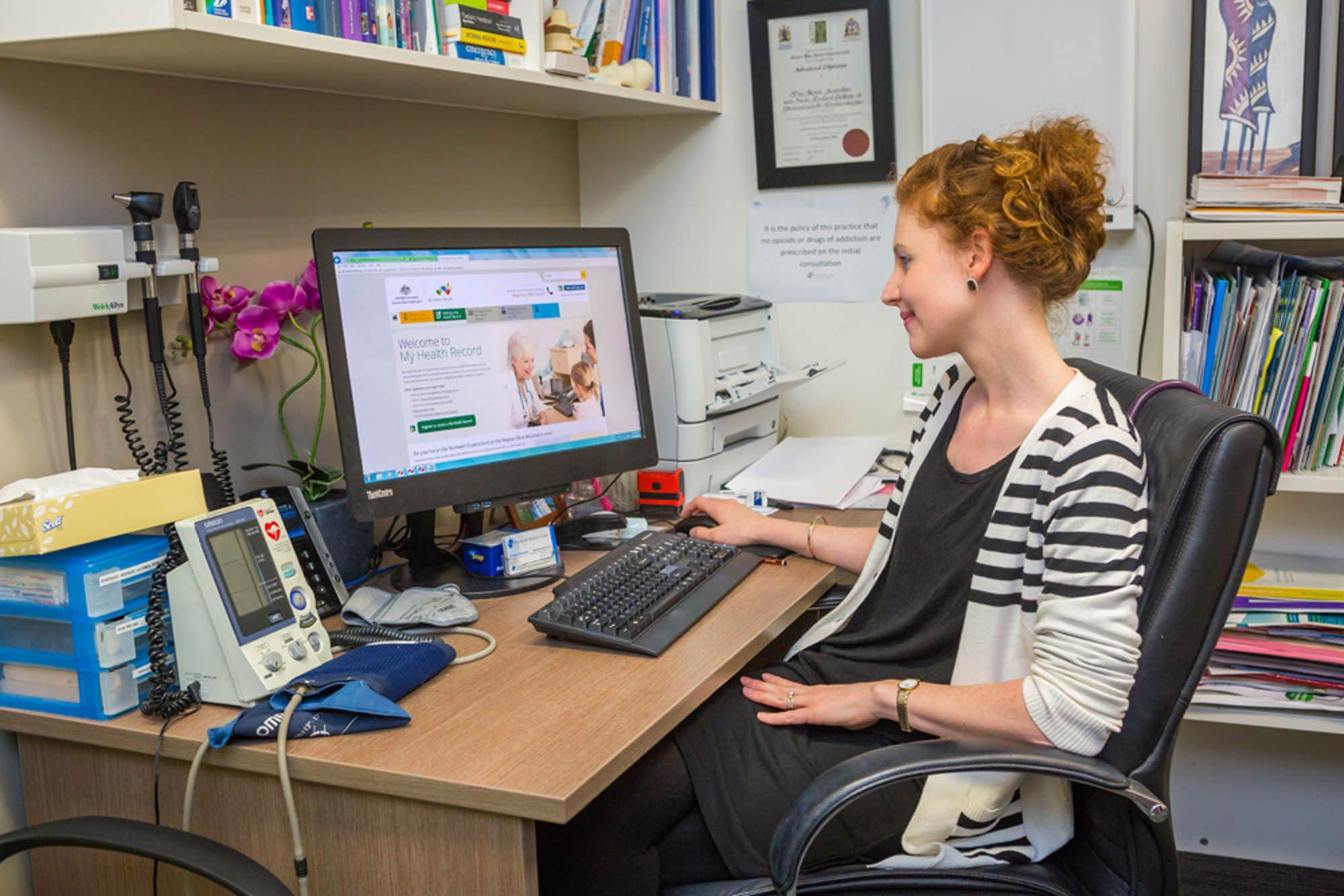 Woman managing patient records and imaging files at a computer with reliable IT support Perth for Allied Health industry.